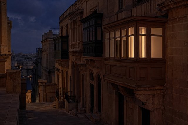 Limestone office facades in Valletta at dusk, one window lit